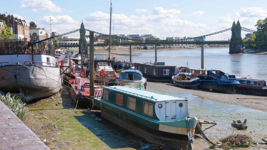 House boats sitting next to a river at low tide thames hammersmith bridge west london